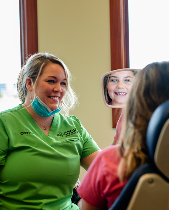 Cook Orthodontics Staff Member Showing Patient Her Smile With Braces
