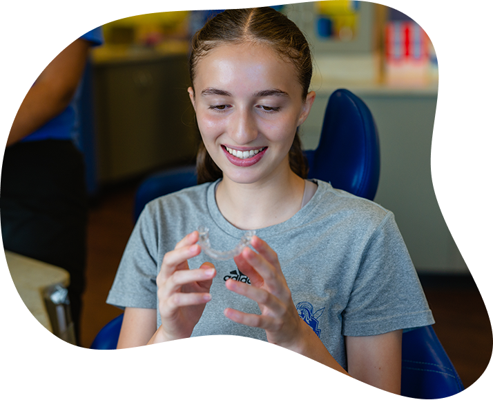 Smiling Girl Holding Clear Aligner